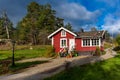 Small traditional red Swedish wooden house. The glazed windows terrace and steps porch are decorated with potted flowers, plants Royalty Free Stock Photo