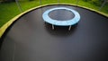 Small trampoline on big one with round mat, size comparison, green lawn background Royalty Free Stock Photo