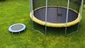 Small trampoline near big one with round mat, size comparison, green lawn background Royalty Free Stock Photo