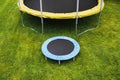 Small trampoline near big one with round mat, size comparison, green lawn background Royalty Free Stock Photo