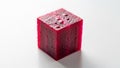 A small translucent red cube rests on a smooth white surface Royalty Free Stock Photo