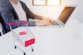 Small trolley cart with woman enjoy shopping on her laptop background