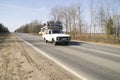 A small truck carries a stack of large-diameter metal pipes