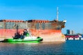 Small tugboat assisting bulk cargo ship in Lithuanian harbor Royalty Free Stock Photo