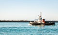 Small Tugboat moving out of safety of harbor in commercial port of Cape Town