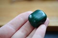 Small tumbled Malachite being held in woman`s hand. Green healing crystal, for prosperity and health. Growth and wisdom Wiccan sym