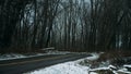 Small, two-lane road leading through forested area during winter, with snow on either side Royalty Free Stock Photo