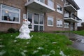 Small ugly snowman melting in the garden of a small residental building in Cambridge. First snow of the 2020 year and children are
