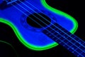 Small ukulele in the darkness under the blue and green light. Background picture.