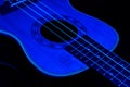 Small ukulele in the darkness under the blue light. Background picture.