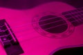 Small ukulele in the darkness under the violet light. Background picture.