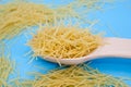 Small uncooked pasta in a wooden spoon / blue background. Close-up. Royalty Free Stock Photo