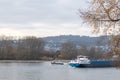 A small vessel passing a river barge on the river Rhine in autumn with branches in the foreground