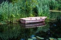 Small vessel reflecting in a creek with green water reeds, Barendrecht, The Netherlands