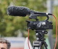 Small video camera on a stable tripod with large microphones films an event