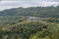 Small village at beautiful green wide valley view landscape among mountains covered with trees under cloudy sky Royalty Free Stock Photo