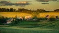 small village in the middle of a hilly agricultural field in the warm light of sunset