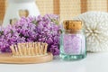 Small vintage glass bottle with purple bath salts epsom salt, foot soak, wooden hair brush and lilac flowers. Royalty Free Stock Photo