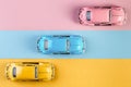 Small vintage retro toy cars on a pink, yellow and blue background