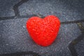 Small vivid red heart on grey pavement