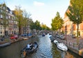 Small water canal in Amsterdam city. Picturesque town landscape with people, boats and old buildings facade in Netherl