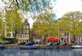 Small water canal in Amsterdam city. Picturesque town landscape with people and old buildings facade in Netherlands wi