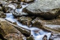 Small waterfall with blue foamy water on wet stones Royalty Free Stock Photo