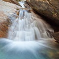 Small waterfall casdcading over rocks in blue pond Royalty Free Stock Photo