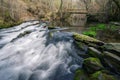 Small waterfall at the end of a river backwater under a wooden bridge Royalty Free Stock Photo