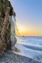 small waterfall that falls on a pebble beach and stops at the sea in the background, scene with a beautiful sunset light. Royalty Free Stock Photo