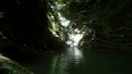 Small waterfall flow into mountain lake between stone walls