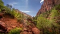 A small Waterfall flowing over the Cliffs overhanging the Trail and Rock Slide of the Lower Emerald Pool Trail in Zion National Pa Royalty Free Stock Photo