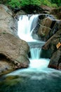 Small waterfall flowing over rocks in nature. Royalty Free Stock Photo