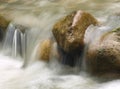 Small waterfall in the mountain river. Beautiful natural background of stones and with flowing, blurring water and foaming. Royalty Free Stock Photo