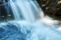 Small waterfall in a mountain stream between rocks, the water is blurred in motion Royalty Free Stock Photo