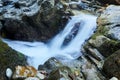 Small waterfall in a mountain stream between rocks, the water is blurred in motion Royalty Free Stock Photo
