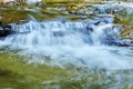 Small waterfall in a mountain stream between rocks, the water is blurred in motion Royalty Free Stock Photo