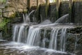 A small waterfall near a water mill shot with a long exposure and blurred water, like milk. Royalty Free Stock Photo