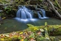 Small waterfall through the rocks covered by the moss in autumn Royalty Free Stock Photo