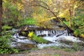 A small waterfall on a shallow river flowing through the morning forest Royalty Free Stock Photo