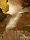 Small waterfall on small mountain stream, mossy sandstone block and water is jumping down into small pool. Water streams with Royalty Free Stock Photo