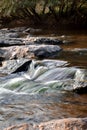 Small waterfall timelapse from rocks smooth waterfall black brown in forest ripples and flow Royalty Free Stock Photo