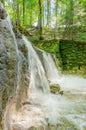 Small waterfall of a wild stream, water flows over an old dam Royalty Free Stock Photo