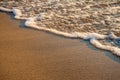 Small wave of the sea meets the sand on the shore of a sandy beach