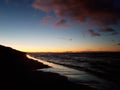 Small wave on the surface of the sea and a dark sandy beach against the blue sky after sunset Royalty Free Stock Photo