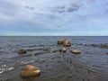 Small Waves Hit Stones in Water of Lake Shore under Blue Sky before Clear Horizon Royalty Free Stock Photo