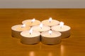 Small wax candles burning on wooden table Royalty Free Stock Photo
