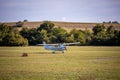 Small white airplane landing on a grass field