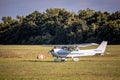 Small white airplane landing on a grass field