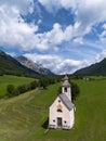 Aerial view of white alpine chapel in green pastoral landscape in Italian Dolomites Royalty Free Stock Photo